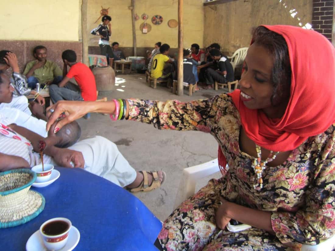A woman pouring coffee for friends at a busy neighbourhood cafe