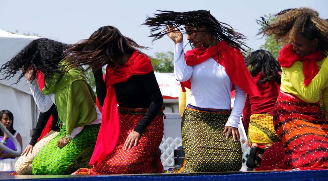 Dancers in traditional dress performing on an outdoor festival stage