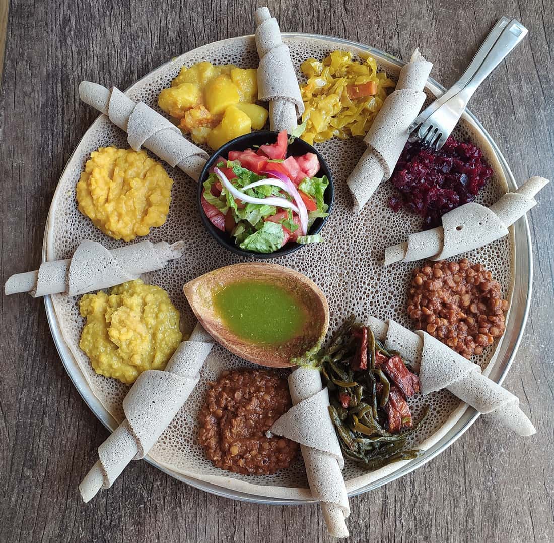 A shared injera platter spread with lentil, vegetable and salad dishes